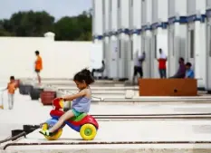  ?? Darrin Zammit Lupi/Reuters ?? A child migrant plays on a tricycle outside prefabrica­ted container houses at the Hal Far Tent Village refugee camp outside Valletta in Malta in September 2014.