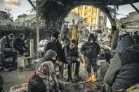  ?? SERGEY PONOMAREV THE NEW YORK TIMES ?? Members of a family warm themselves around a fire near a collapsed building in Antakya, Turkey. After an earthquake last week that killed at least 33,000 in the region, many Syrian refugees have found their lives upended yet again.