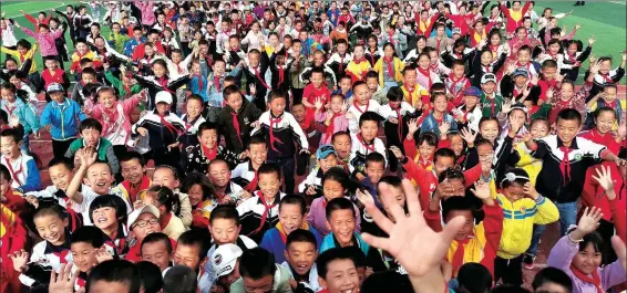  ?? XIE HAILONG / FOR CHINA DAILY ?? Students welcome visitors to a primary school in Lyuzhou, Gulang county, Wuwei, Gansu province, on June 27, 2019. The school has modern facilities and enrolls more than 1,000 students from 16 ethnic groups, with many of them being migrants from poor areas.