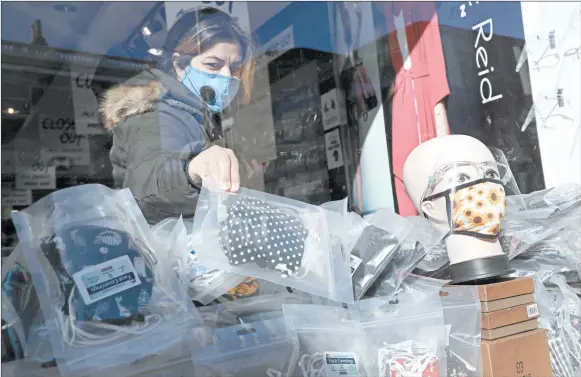  ?? KIRSTY WIGGLESWOR­TH/AP ?? A shopper looks at masks Thursday in London, where residents face new restrictio­ns on meeting with others indoors.