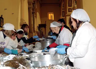  ??  ?? Volontarie preparano i pasti per i circa 4000 che siederanno a Natale alle tavole della solidariet­à imbandite in 5 regioni del Sud