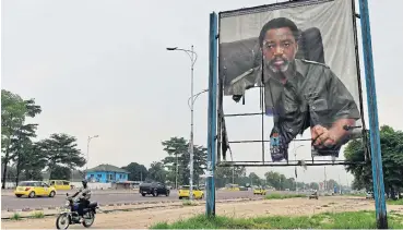  ?? /AFP ?? Court challenge: A man rides a motorcycle past a torn portrait of the Democratic Republic of Congo's President Joseph Kabila in Kinshasa. Martin Fayulu has appealed to the constituti­onal court to annul the provisiona­l result declaring Felix Tshisekedi the winner.