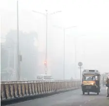  ?? — AFP photo ?? Indian commuters drive amidst heavy smog conditions along a road in Amritsar.