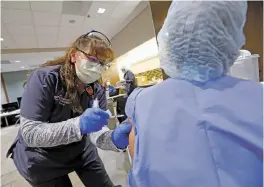  ??  ?? BELOW: Joann Perea, a critical care registered nurse and clinical supervisor in the ICU, gives a vaccine injection to Linda Reid, who works in Christus St. Vincent’s COVID-19 unit.