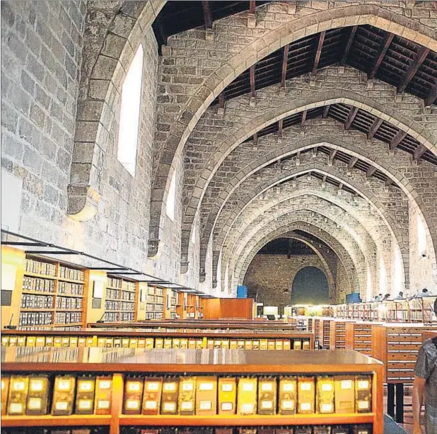  ??  ?? La gran sala gótica de la biblioteca de Catalunya, convertida en sala de lectura, aún con los cedularios con las antiguas fichas manuscrita­s