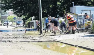  ??  ?? Teamwork . . . Volunteers clean up the mud outside Roxburgh Area School.