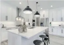  ??  ?? The kitchen sparkles in white and has an island big enough for eating.