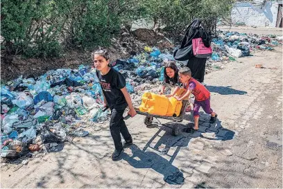  ?? AFP ?? Una niña palestina arrastra un carro con bidones de plástico con ayuda de otros dos niños en Rafah (Gaza)