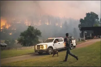  ?? ASSOCIATED PRESS ?? A man runs to a truck, Saturday, as a wildfire called the McKinney fire burns in Klamath National Forest. The blaze is one of three burning in California.