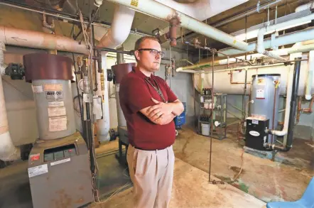  ?? MICHAEL SEARS / MILWAUKEE JOURNAL SENTINEL ?? Jonathan Mitchell, director of finance and operations at the St. Francis School District, stands in front of boiler heating units at Deer Creek Intermedia­te School. Republican­s are pushing to end a tax law schools use for energy-related projects.