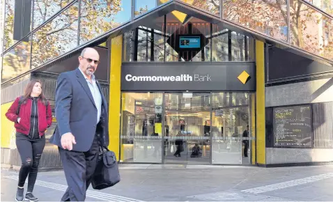  ?? AFP ?? People walk past a branch of Commonweal­th Bank of Australia in Melbourne.