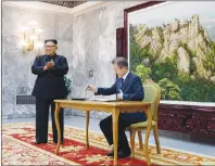  ?? SOUTH KOREA PRESIDENTI­AL BLUE HOUSE VIA AP ?? South Korean President Moon Jae-in writes on a visitor’s book as North Korean leader Kim Jong Un stands at the northern side of Panmunjom in North Korea.