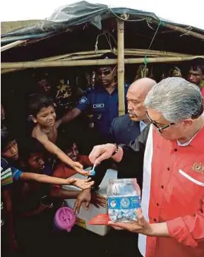  ??  ?? Ahmad Zahid mengagihka­n gula-gula kepada kanak-kanak Rohingya ketika melawat penempatan pelarian Rohingya di Kem Kutupalong, Cox's Bazar, semalam.