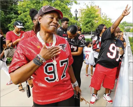  ?? CURTIS COMPTON / CURTIS.COMPTON@AJC.COM ?? Elisha Jarrett (left), the mother of Falcons defensive tackle Grady Jarrett, could get no closer than above the players’ parking lot. She and family yelled their encouragem­ent, and she and her son shared a long-distance fist bump.