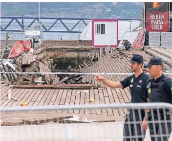  ?? FOTO: DPA ?? Zwei Polizisten gehen an dem eingestürz­ten Holzsteg vorbei. Der Steg brach während eines Festivals unter dem Gewicht der Massen zusammen, einige Besucher fielen ins Wasser. Rund 310 Menschen wurden bei dem Unfall verletzt.