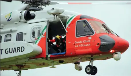  ??  ?? A rescue crew member looks on from Helicopter Rescue 115 on Sunday evening as the rescue services help to winch to safety a swimmer who got into difficulty swimming at the Nun’s Strand.