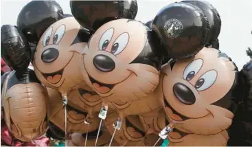  ?? MICHEL EULER/AP 2015 ?? Mickey Mouse balloons at Disneyland Paris. An earlier version of the mouse is entering the public domain.