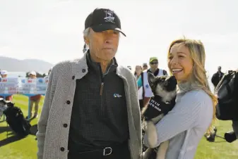  ?? Eric Risberg / Associated Press ?? Clint Eastwood and Kira K. Dixon stand on the 18th green on Wednesday and wait to hit during the fivehole celebrity challenge event of the AT&T Pebble Beach National ProAm.