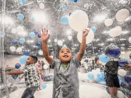  ?? Photos by Brett Coomer/Staff photograph­er ?? Mason Parrish plays in a balloon-filled snow globe during the “Special Needs” Family Day event Saturday in Houston.