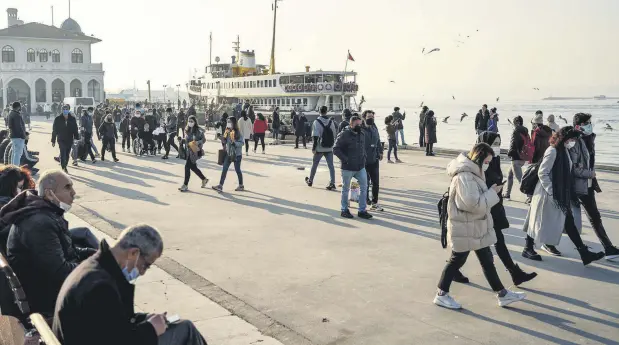  ??  ?? People wearing face masks as protection against the coronaviru­s walk by the seaside in Istanbul’s Kadıköy district, Turkey, Feb. 23, 2021.