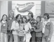  ?? ?? Supporters of the Mendocino Whale War pose outside Crown Hall with J. D. Mayhew’s poster for the 1st Annual Whale Festival. From left: Ellen Findlay Herdegen, Bill Wilson, Sue Golden, baby Brenden Cusick, Heidi Cusick, Barry Cusick, Sally Welty, Lee Welty. Courtesy of the Kelley House Museum.