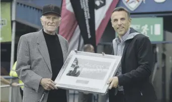  ??  ?? ↑ Gregg foils a Tottenham Hotspur attack at White Hart Lane in 1959; Right, he is presented with a picture of the Busby Babes by former United player Phil Neville at a Manchester United v Celtic Under-19 match at Coleraine in 2018; Below, the Munich clock at Old Trafford.