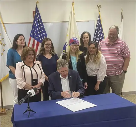  ?? Submitted photo ?? Rep. Mia Ackerman and other bill supporters watch as Gov. Dan McKee signs the bill into law.