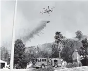  ??  ?? Un helicópter­o de extinción de incendios lanza agua en una ladera amenazada por la conflagrac­ión.