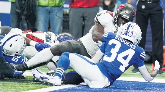  ?? MICHAEL CONROY/AP PHOTOS ?? Buccaneers QB Tom Brady (left) improved his all-time record against the Colts to 16-4. Bucs running back Leonard Fournette (above) scores one of his four TDs.