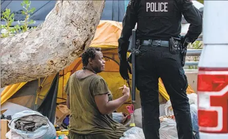  ?? Irfan Khan Los Angeles Times ?? A HOMELESS PERSON in Los Angeles gathers his belongings prior to a cleanup. The city’s actions are at the center of a lawsuit.