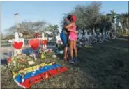  ?? GERALD HERBERT — THE ASSOCIATED PRESS ?? This file photo shows Denyse Christian, hugging her son Adin Christian, 16, a student at the school, at a makeshift memorial outside the Marjory Stoneman Douglas High School, where 17students and faculty were killed in a mass shooting in Parkland, Fla.