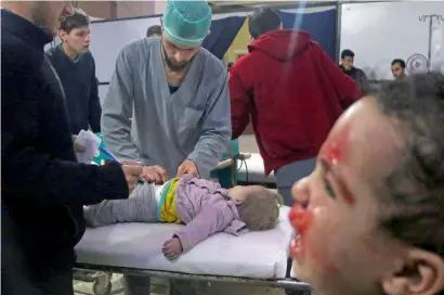  ?? AFP ?? Syrian medics tend to a baby as a child cries next to them at a makeshift clinic in the besieged Eastern Ghouta region. —