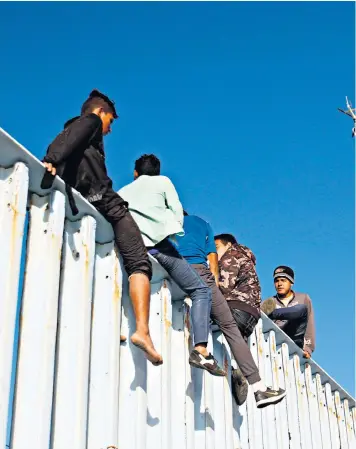  ??  ?? Migrants sit on top of the border fence separating Mexico and the United States after the first breakaway group arrived in Tijuana