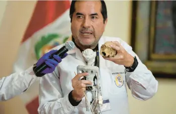  ?? MARTIN MEJIA/AP ?? No, not aliens: Forensic archaeolog­ist Flavio Estrada shows a doll seized by authoritie­s before it was shipped to Mexico, during a news conference Friday at the Archeology Museum in Lima, Peru. Estrada said two dolls and an alleged three-fingered hand were constructe­d of paper, glue, metal, human and animal bones — debunking theories of their alien origins.