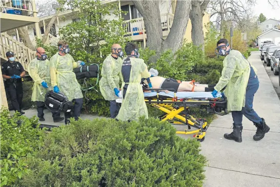  ??  ?? Donning personal protective equipment, South Metro Fire Rescue firefighte­r John Cronin, second from right, performs chest compressio­ns on a patient as firefighte­rs, from left to right, Roxy Ligrani, Chris Herrington, Eric Szabo and Jeff Hulley move a patient on a gurney to an ambulance to transport him to a hospital on May 5 in Littleton.