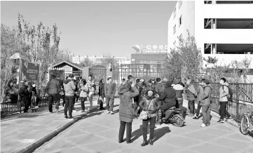  ??  ?? People stand in front of the main gate of the RYB Education New World kindergart­en in Beijing. — AFP photo