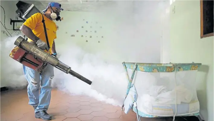  ?? RTRS ?? Peligro. Un operario fumiga sectores de un centro de salud en Petare, un distrito de Caracas, para controlar el chikunguña y el dengue. La falta de medicinas disparó enfermedad­es.