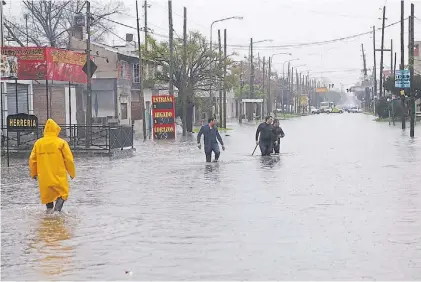  ??  ?? En Quilmes. Calles anegadas y caídas de postes de luz, una escena que se repitió en el Gran Buenos Aires.