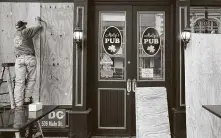  ?? Elizabeth Conley / Staff photograph­er ?? Dave Denton puts plywood on Molly’s Pub in downtown Houston before today’s planned rally for George Floyd.