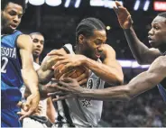  ?? Tom Reel / San Antonio Express-News ?? The Spurs’ Kawhi Leonard rips away a rebound from Andrew Wiggins (left) and Gorgui Dieng.