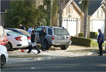  ?? Associated Press ?? Fresno, California, police investigat­ors work the driveway Monday where a shooting took place Sunday at a house party which involved multiple fatalities and injuries.