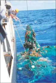  ?? AFP / Getty Images ?? This handout photo released last month by Ocean Cleanup shows Mega Expedition mothership Ocean Starr crew pulling a ghost net from the Pacific Ocean filled with litter. Researcher­s have engineered an enzyme that eats plastic and may eventually help...