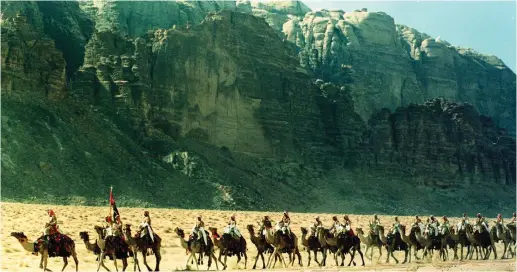  ??  ?? DESERT GUARDS on camels march past the towering rock-cliffs of Wadi Rum in southern Jordan not far from the area where the Arab tribes under the Hashemites marched forth during the Arab revolt in 1917. The shadow of those years still hangs heavy on the...