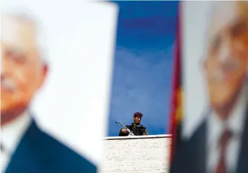  ?? (Reuters) ?? A PALESTINIA­N Security Forces member stands above a poster of Palestinia­n Authority President Mahmud Abbas.