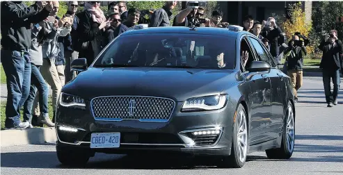  ?? FRED CHARTRAND / THE CANADIAN PRESS FILES ?? People watch as an autonomous car drives down an Ottawa street as the City of Ottawa and BlackBerry QNX demonstrat­e the vehicle in October. A federally-funded study recommends Canada “fast-track” self- driving technology.