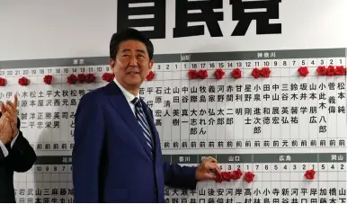  ?? (Kim Kyung-Hoon/Reuters) ?? PRIME MINISTER Shinzo Abe, leader of the Liberal Democratic Party (LDP), puts a rosette next to his name after the lowerhouse election yesterday at LDP headquarte­rs in Tokyo.