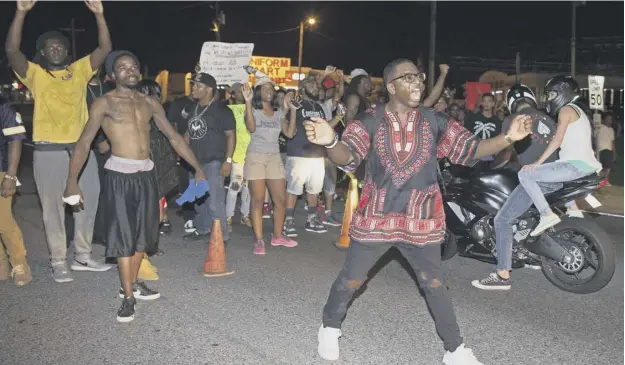  ?? PICTURE: MAX BECHERER/AP ?? 0 A group of protesters blocks Airline Highway, which passes in front of the Baton Rouge Police Department headquarte­rs, on Saturday night