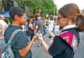  ?? STAFF PHOTO BY TIM BARBER ?? Chenelle Caudle, left, and the Rev. Claire Brown light candles outside City Hall during Tuesday night’s vigil.