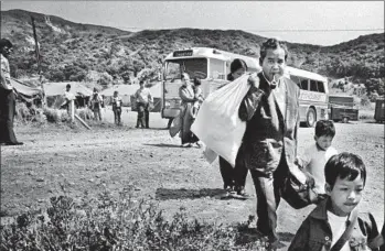  ?? Don Bartletti ?? VIETNAMESE REFUGEES file off a Greyhound bus at the Camp Talega relocation center at Camp Pendleton on June 12, 1975. This is where Julie Lam, then 14, and her family got off the bus.