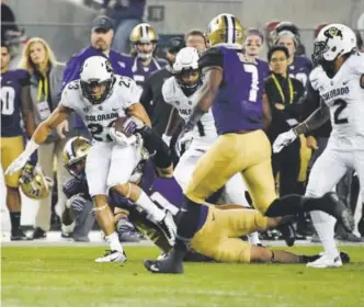  ?? Andy Cross, The Denver Post ?? CU’s Phillip Lindsay (23) looks for running room against the Washington defense in the Pac-12 championsh­ip game Friday night.